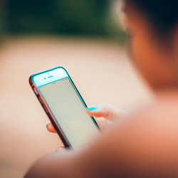 Image of a woman looking at her mobile phone with high rise buildings in the background